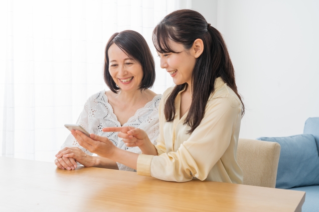 結婚相談所埼玉　スマートフォンを一緒に見ている笑顔の母娘の画像です。