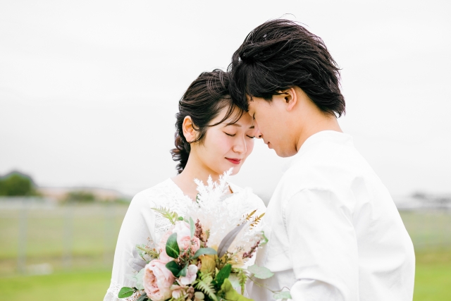 結婚相談所埼玉　ブーケを持ち目を閉じている幸せそうな表情の女性が男性と向かい合いおでこをくっつけている画像です