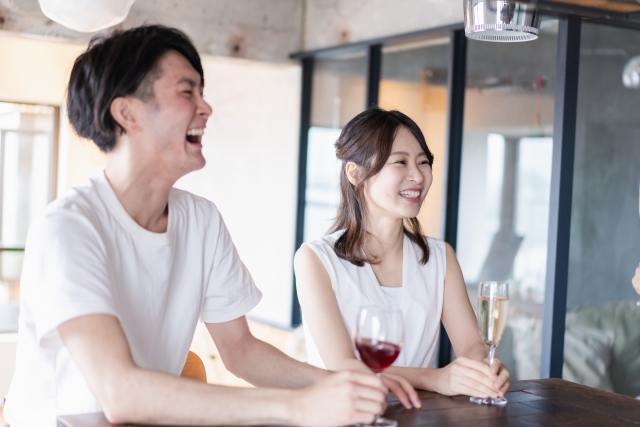 結婚相談所埼玉　カウンターに並んで座り、グラスを手に持ち笑顔の男女の画像です。