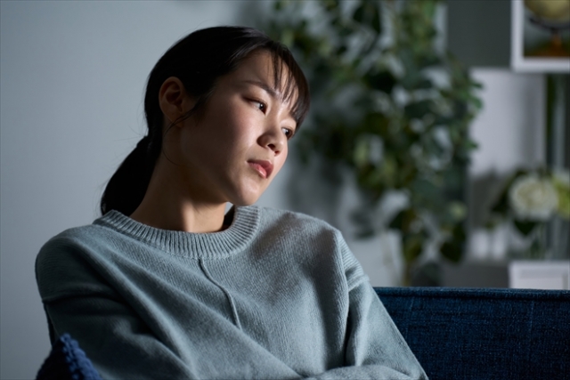 結婚相談所埼玉　薄暗い部屋で一人悩む女性の画像です。