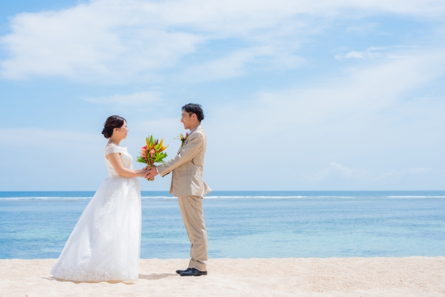 結婚相談所埼玉　砂浜で向かい合い手を取り合うウエディングの二人