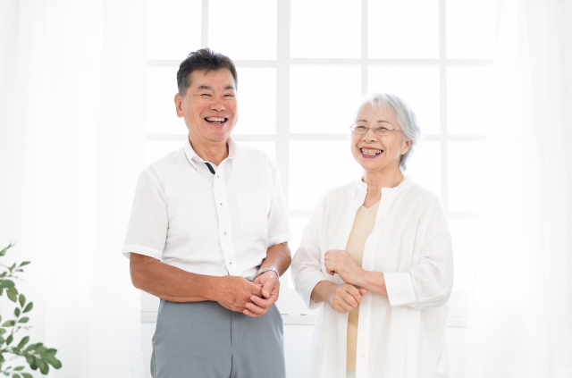 結婚相談所埼玉　窓際に幸せそうな笑顔で並んで立っている高齢の男女の画像です。