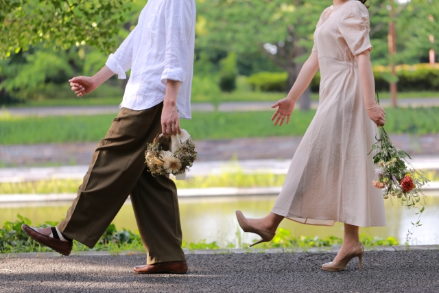 結婚相談所埼玉　カップルが公園で歩いている写真です。手を大きく振り、花束を持っています。
