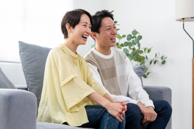 結婚相談所埼玉　40代～のカップルがソファに座って笑っている写真です。